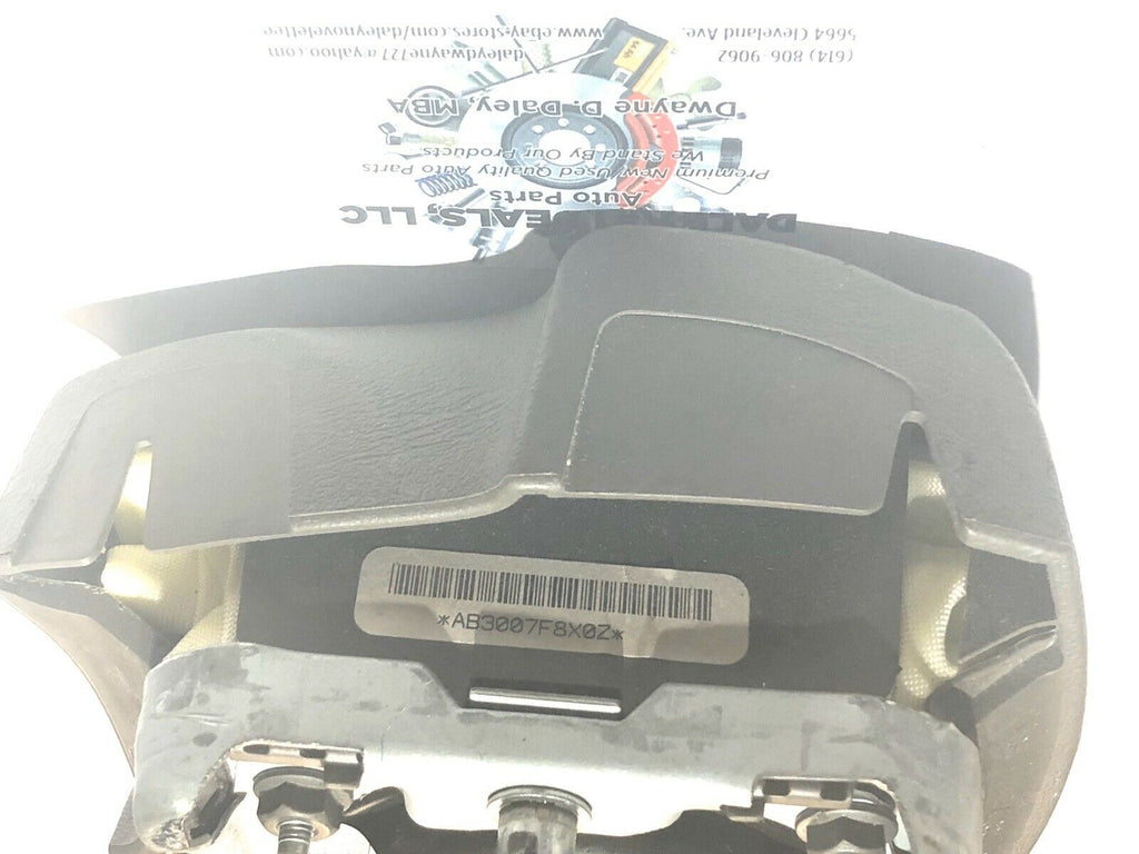 Front view of OEM black driver steering wheel airbag for 2004-2006 Cadillac Escalade with textured cover, Cadillac crest emblem, and embossed AIRBAG text.