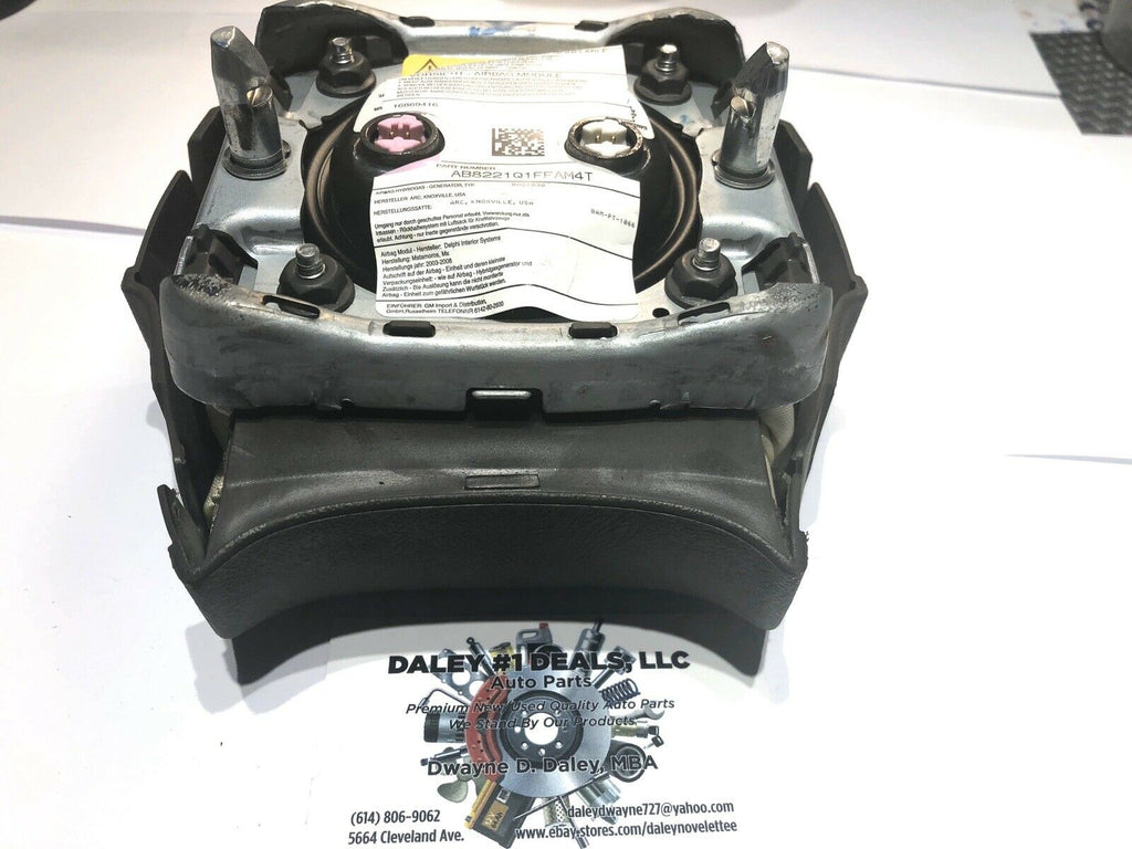 Front view of OEM black driver steering wheel airbag for 2004-2006 Cadillac Escalade with textured cover, Cadillac crest emblem, and embossed AIRBAG text.