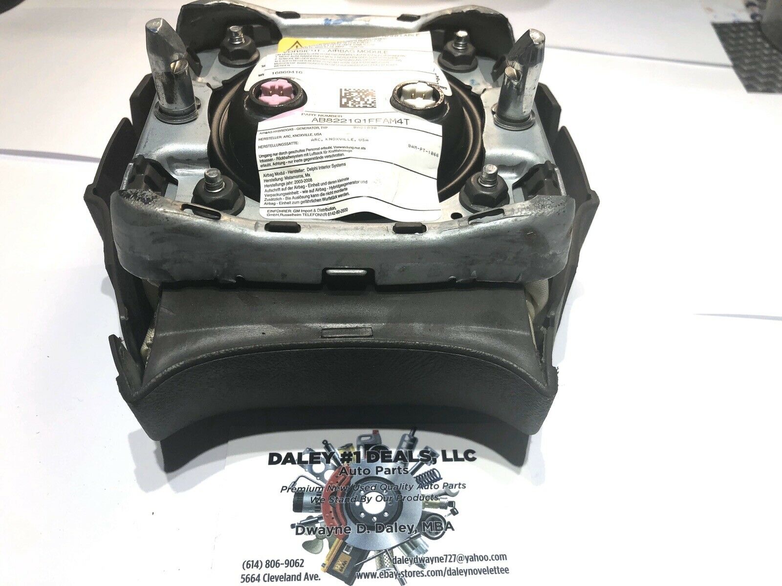 Front view of OEM black driver steering wheel airbag for 2004-2006 Cadillac Escalade with textured cover, Cadillac crest emblem, and embossed AIRBAG text.